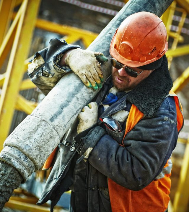 Construction worker in safety gear handling equipment on an active site.